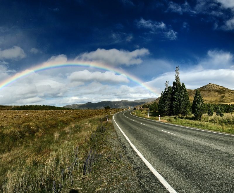 A rainbow over the road in the middle of nowhere.